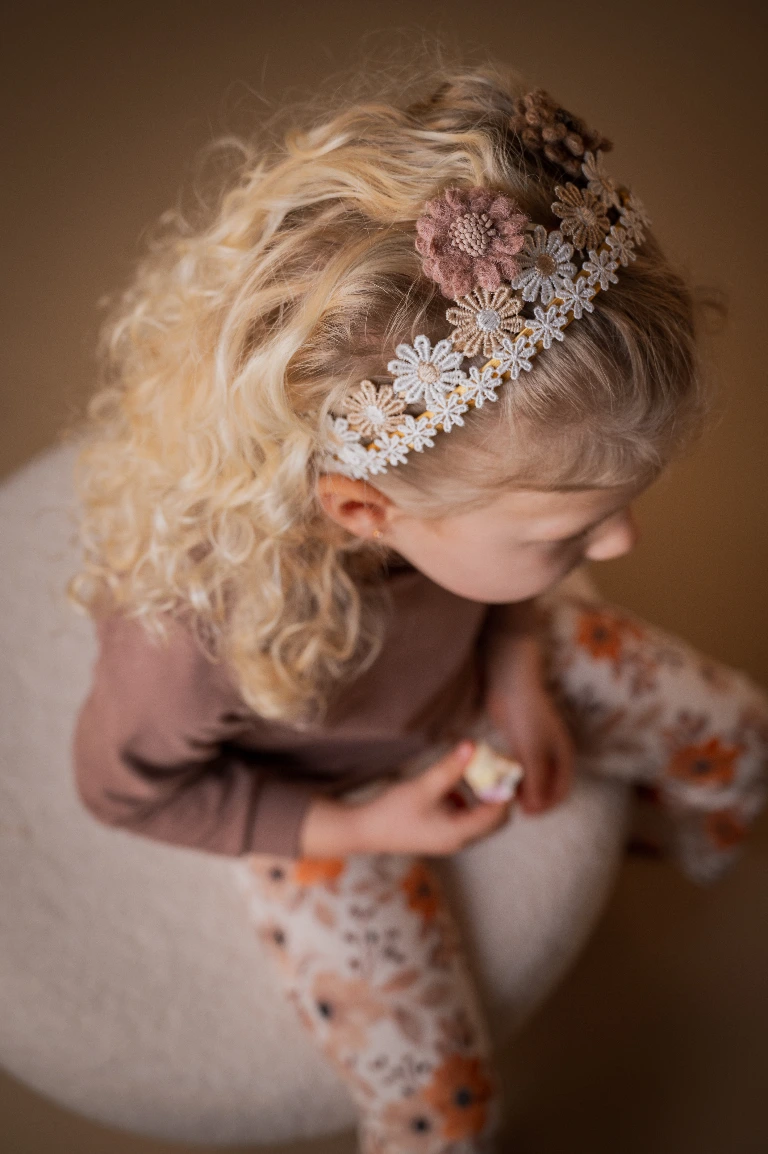peuter met bloemen haaraccessoires closeup in warme kleuren