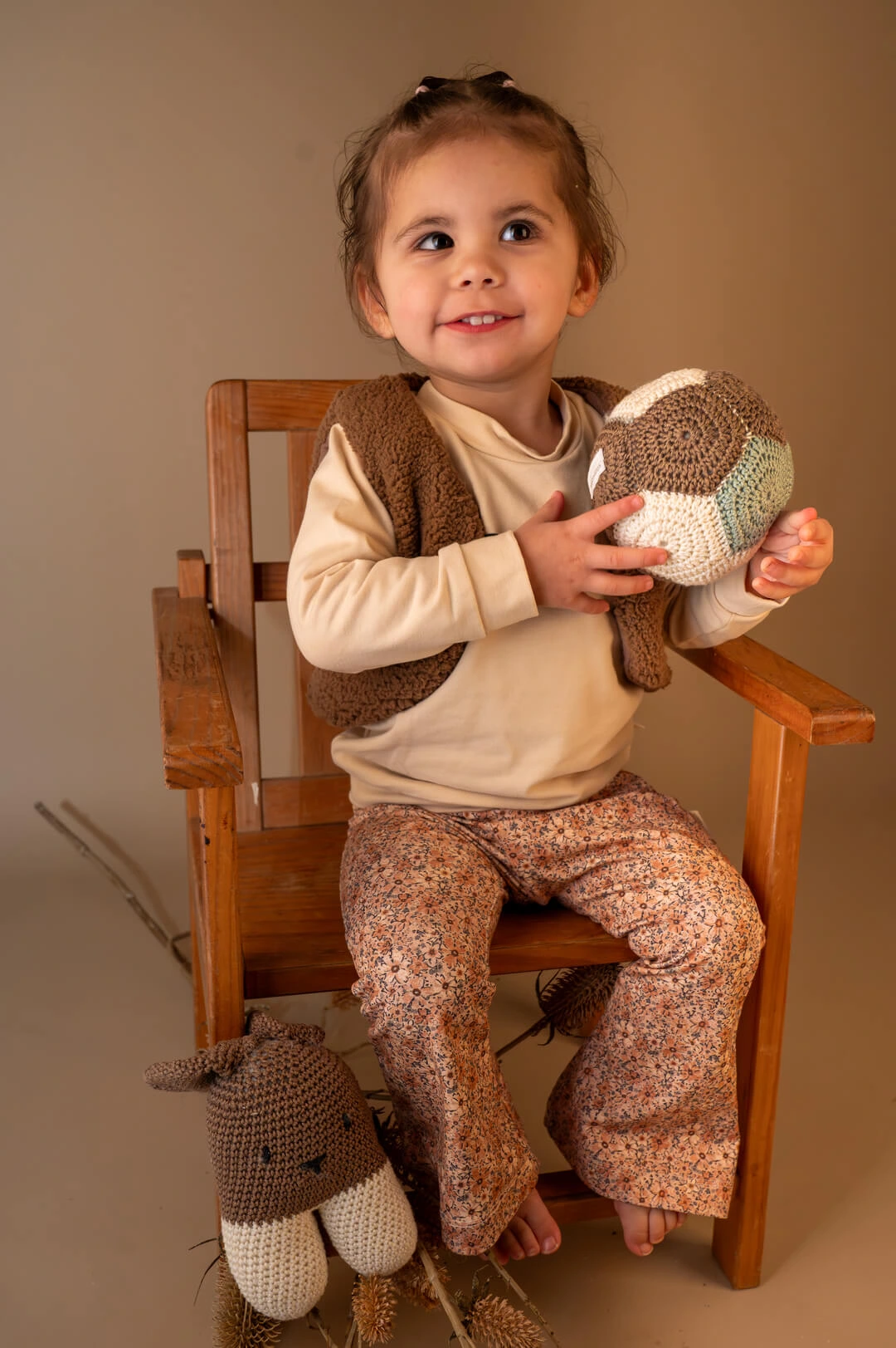 peuter met gehaakte konijn knuffel op houten stoel, zachte baby-en kinderkleding in neutrale kleuren van Twensies